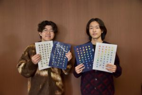 クリアファイルをデザインした2名の学生がそれぞれ自分がデザインしたクリアファイルをもって並ぶ写真