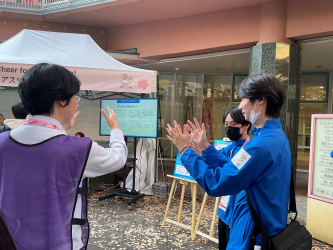 本学サポートスタッフの学生が、訪れた方にサインエールを教える様子