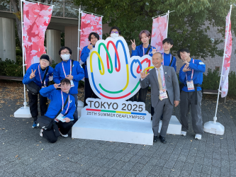 本学サポートスタッフの学生と学長が、東京2025デフリンピックのマークのオブジェで撮った記念写真