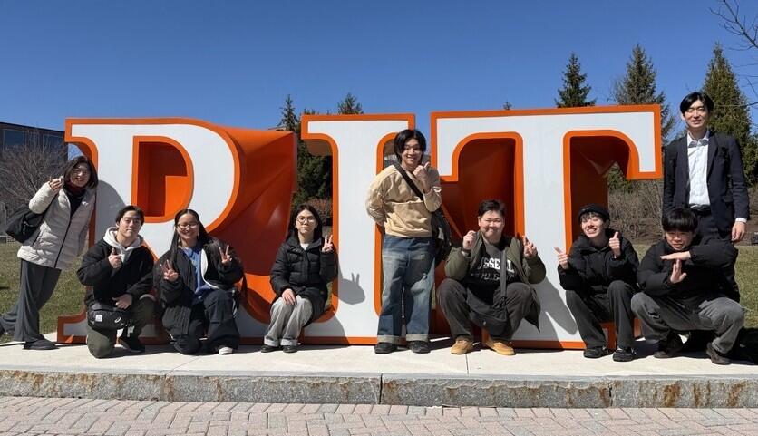 大学名である「RIT」のモニュメントとともに撮影した集合写真