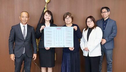 集合写真。左から石原学長田口さん吉澤氏磯田助教鈴木教授。田口さんと吉澤氏がカレンダーを持っている。