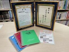 川柳コンテストの記念品で、賞状と作品を入れたフォトフレーム、PEPNet-Japanのロゴが入ったメモ帳、作品に対するコメントを記入したThanksカードの3点