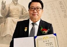 文化勲章を身につけ表彰状を持つ劉教授の写真