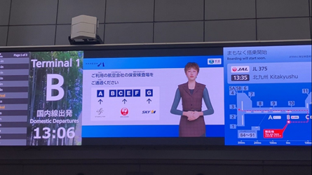 羽田空港の大型サイネージに表示される手話CG。上のバナーには羽田空港ロゴと手話のロゴが配置されている。画面左側には、「ご利用の航空会社の保安検査場をご通過ください。」という文字と共にA←スターフライヤー、B・C・E・F←JAL、G←スカイマークという図がある。画面右側には、手話アバター「KIKI」が表示されている。